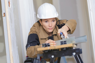 female builder using a machine electronic table saw cutting