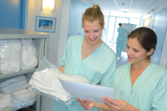 portrait of 2 nurses checking laundry list at the hospital