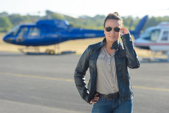 pretty pilot woman posing with helicopter in the background
