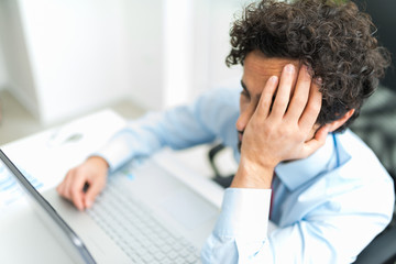 Stressed businessman looking at his computer