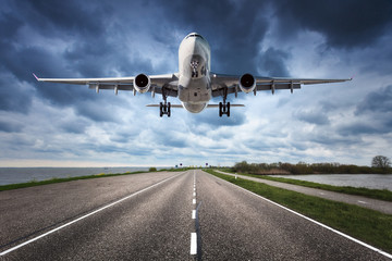 Airplane and road. Landscape with big white passenger airplane is flying in the cloudy sky over the...