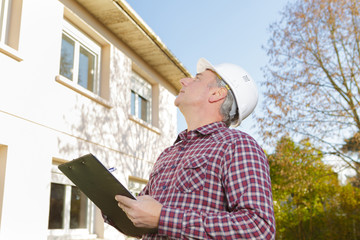 male supervisor reading clipboard at construction site on sunny day