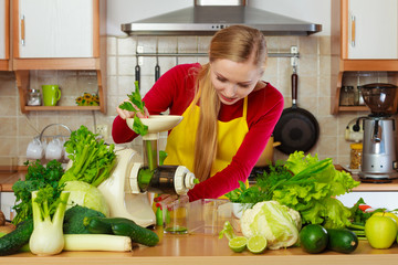 Woman in kitchen making vegetable smoothie juice