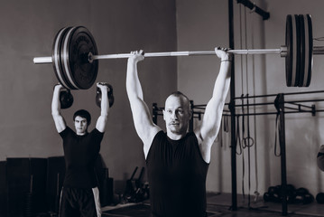 Strong man lifting a barbell during crossfit workout at gym