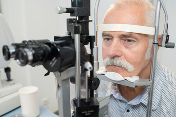 close-up of an optometrist checking senior male patient vision