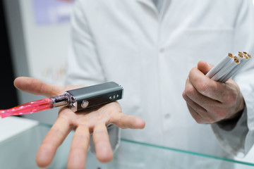 man is holding vaporizer and conventional tobacco cigarettes