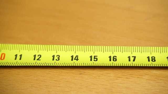 Tape measure on the brown wooden background.  Construction, engineering, repair concept. Dolly sliding shot 4K ProRes HQ codec