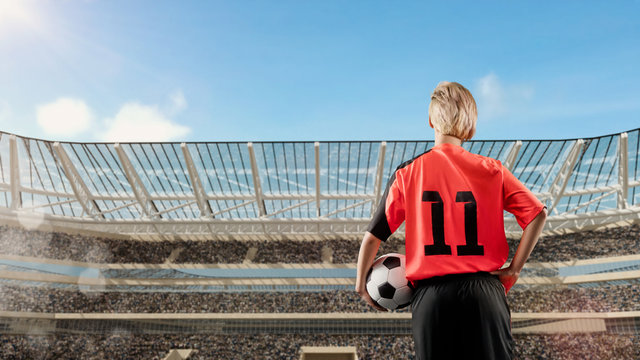 female soccer player standing with the ball against the crowded stadium on background