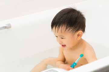 Asian baby uses toothbrush in the bathroom