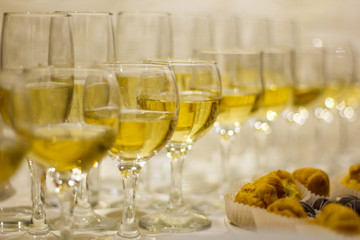a row of glasses filled with champagne are lined up ready to be served. Selective focus