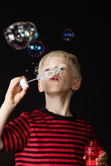 Fototapeta premium Young boy having fun blowing soap bubbles