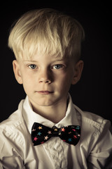 Handsome little blond boy in a stylish bow tie