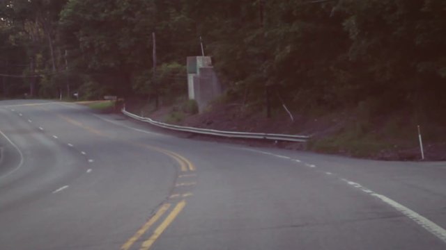 Driving down bendy road with indie film color grade during evening