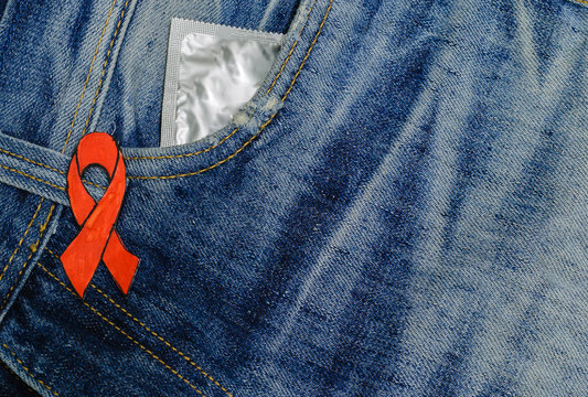 Red is the symbol of World AIDS Day and condoms in jeans - prevention of AIDS.