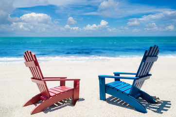 Red and blue beach chairs near ocean