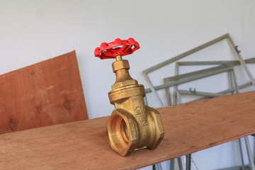 brass valve with red knob in a factory plumber. on wooden floor background
