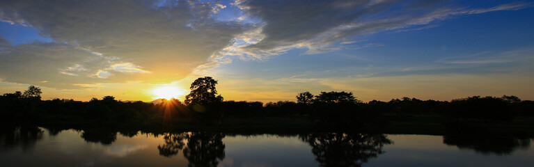 Panorama sunset beautiful colorful landscape and silhouette tree mountain river reflect in sky twilight time