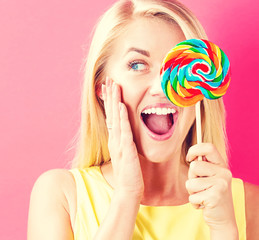 Young woman holding a lollipop on a pink background