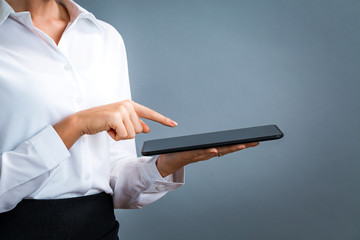 Young woman using her tablet on a gray background
