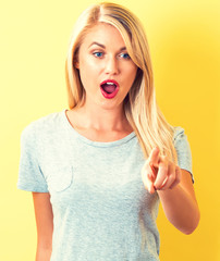 Young woman pointing something on a yellow background