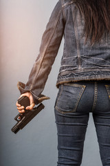Woman in jeans is holding a gun in her hand with light effect.