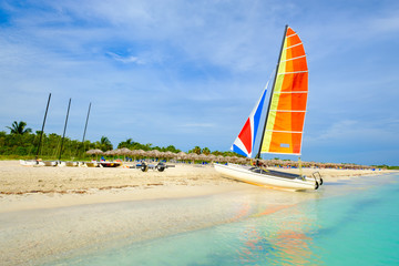 The tropical beach of Varadero in Cuba with a colorful sailboat