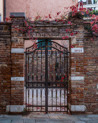 Iron Gate in Brick Wall with Red Leaves, Venice, Italy