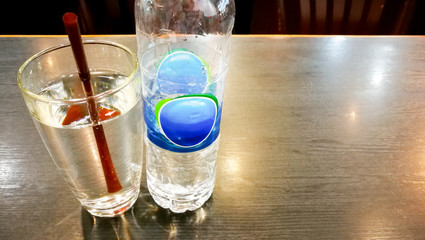 Bottle drinking water and a glass of water with brown straw