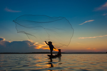 Silhouette,Two fishermen using nets for fishing,sun background.