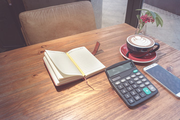 hot mocha coffee, calculator and smart phone with working book on the wooden table