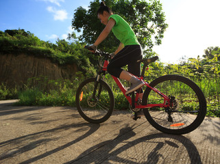 Fototapeta na wymiar woman cyclist cycling on sunrise forest trail