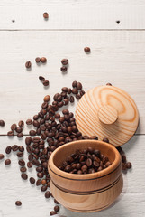 Coffee beans scattered from a Cup on white wooden background, wooden utensils,
