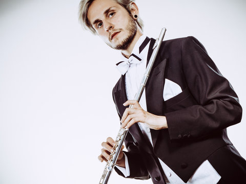 Male flutist wearing tailcoat holds flute