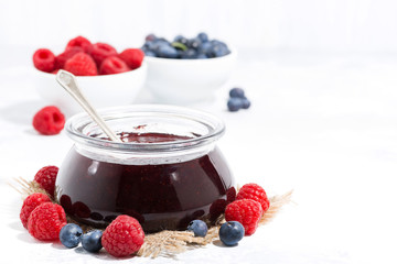 raspberry and blueberry jam in a glass jar on white background