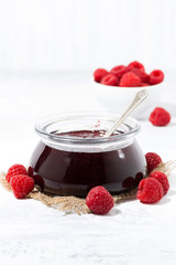 raspberry jam in a glass jar on white background, vertical
