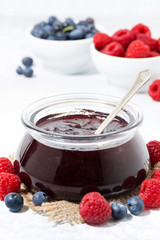 raspberry and blueberry jam in a glass jar, vertical closeup