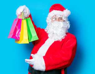 Funny Santa Claus have a fun with shopping bags on blue background