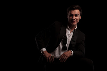 seated man in tuxedo is laughing