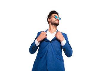 elegant man in sunglasses pulling his collar like superman