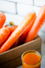 Refreshing smoothies of carrots, pumpkins, mangoes and a box of carrots against a white wall. Glass with carrot smoothies and carrots