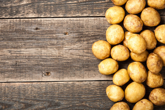 Raw potato on wooden background
