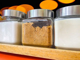 A dozen glasses of white sugar, brown sugar and artificial cream for filling in hot drink on abstract background