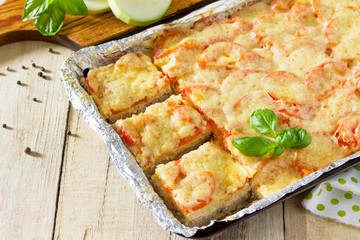 Baked zucchini with meat, rice, tomatoes and cheese on a wooden kitchen table.