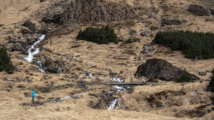 Trekking man scale with majestic waterfall mountain size. How powerful nature is compare to human