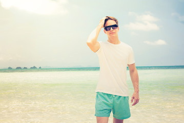 Handsome man wearing casual clothes and sunglasses at the beach in summer