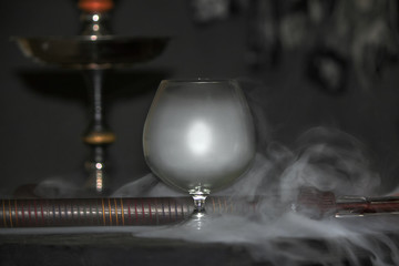 Heavy hookah smoke under a brandy glass on a gray background, hookah tube