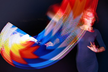 Girl actress with light emitting diodes, light show with red, blue, orange colors, abstract background and arts, colorful lights around the beautiful young woman artist dancing at night
