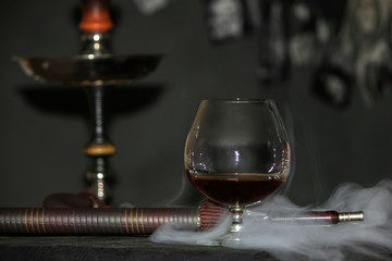 Heavy hookah smoke with a brandy glass on a gray background, hookah tube