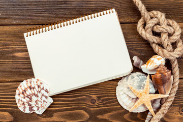 Shells and notepad on wooden table. Top view with copy space