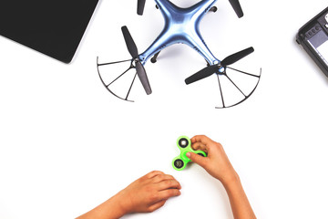 Kids hands playing with fidget spinner toy. Drone and remote controller on white background.